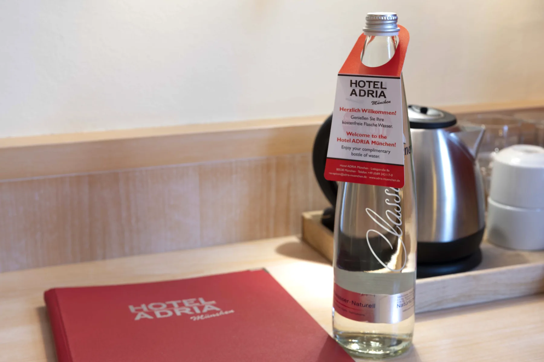 Kostenfreie Flasche Wasser mit Willkommensanhänger auf dem Zimmer, Hotel ADRIA München